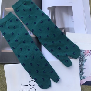 Detailed close-up of green Tabi split-toe socks with blue numbers on top of magazines