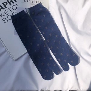 Close-up of navy blue Tabi socks with yellow numbers on a minimalist white fabric background