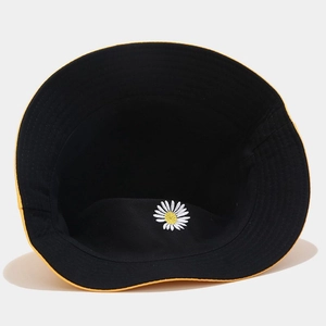 Detailed embroidery of a white daisy on the inner crown of a reversible bucket hat