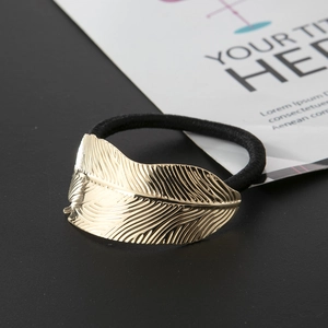 Detailed close-up of golden metal leaf texture and black elastic hair tie
