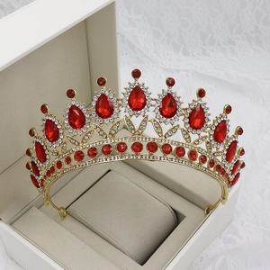 Detailed close-up of a gold baroque bridal crown with red teardrop rhinestones in a gift box