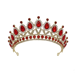 Detailed close-up of golden Baroque crown with red teardrop rhinestones and metal loops