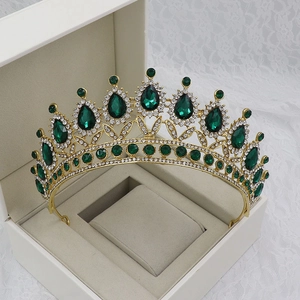 Detail of baroque gold crown featuring emerald green teardrop crystals in a jewelry box