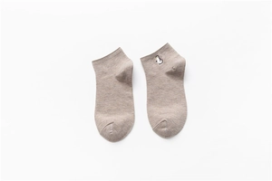 Detail of light brown cotton socks featuring a small cute penguin embroidery on the cuff