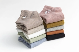 Detailed stack of colorful cotton socks with cute animal embroidery on a white backdrop