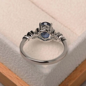 Anillo elegante de plata con zafiro azul ovalado y circón en un estuche para joyería