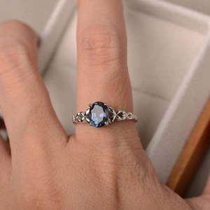 Anillo de moda con zafiro azul ovalado y banda grabada calada sobre joyero
