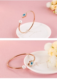 Détail du bracelet jonc or rose avec perle et breloque Main de Fatima en émail bleu