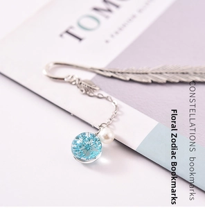 Detailed view of silver feather bookmark with blue dried flower glass pendant and pearl