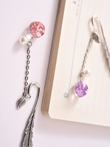 Close-up of vintage silver feather bookmark with dried flower pendant and pearl tassel
