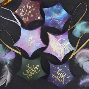 Star shaped wedding candy boxes in mixed colors with gold foil lettering and silk ribbons