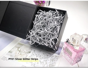 Sparkling silver shredded raffia filling inside a premium black gift box with perfumes