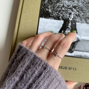 Close-up of a silver 925 cross ring with zircons worn by a model on a vintage magazine
