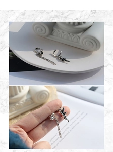 Detailed view of silver asymmetric angel earrings with long vintage chain elements