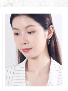 Close-up of a silver fairy wing earring worn by a model with detailed metal textures