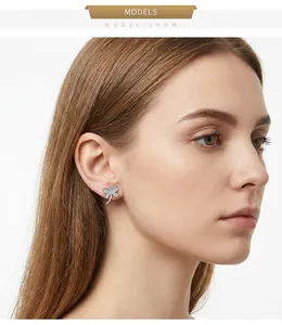 Close-up of a silver dragonfly stud earring on a model ear, minimalist style