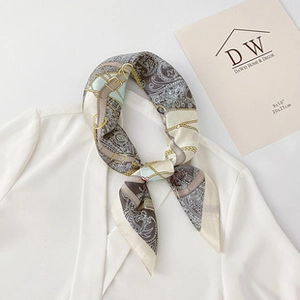 Detail view of paisley and chain print silk scarf styled on a white blazer