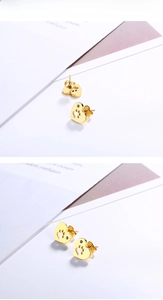 Détail de boucles d'oreilles cœur dorées avec empreinte de patte évidée et petit cristal