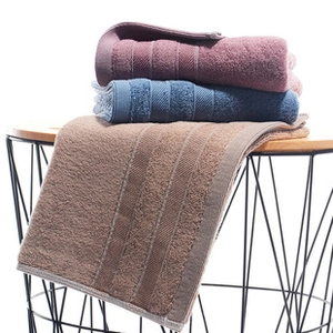 Detailed texture of coral fleece towels in purple, blue, and brown hanging on a rack