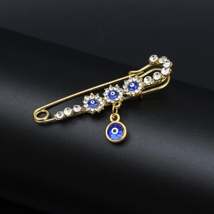 Detailed macro view of golden angel wing brooch pin with blue evil eye charms and crystals