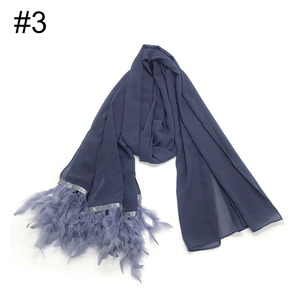 Primer plano de una bufanda de gasa azul con elegantes flecos de plumas a juego