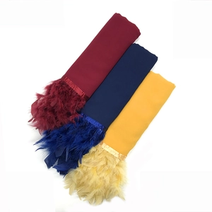Detalle de bufandas de gasa en granate, azul y amarillo con flecos de plumas a juego