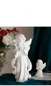 Close-up of praying angel sculptures with detailed flower crowns and carved wing textures