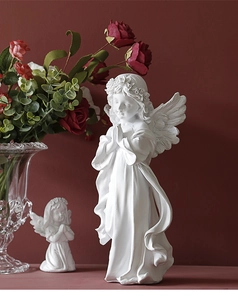 Detail of white resin angel prayer sculptures with elegant red rose floral arrangement