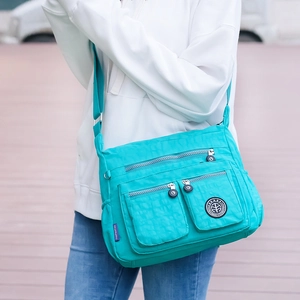 Detail view of turquoise multi-pocket nylon crossbody bag with durable zippers