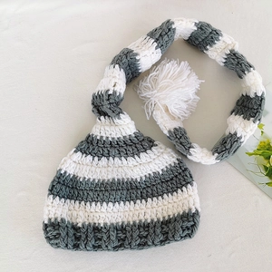 Detailed knit texture of a handmade gray and white striped baby hat with long tail