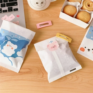 Cute cartoon bear paper storage bags with colorful clips on a wooden tabletop