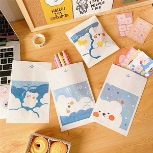 Detail of four mini paper storage bags with cute cartoon bears on a wooden desk setup