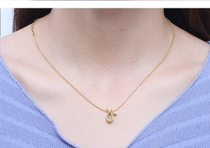 Detail of a minimalist gold snake pendant necklace with a delicate chain worn by a model