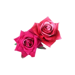 Top view of two lifelike red velvet artificial roses hair clip on plain white backdrop