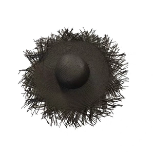 Overhead view of a black hand-woven straw sun hat with stylish frayed edges on white background