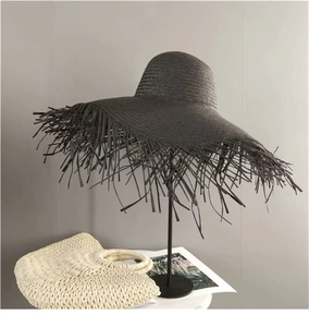 Dark grey hand-woven straw sun hat with large brim and frayed fringe edges for summer beach