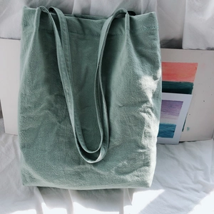 Detail of the sage green linen tote bag showing natural texture and long shoulder straps