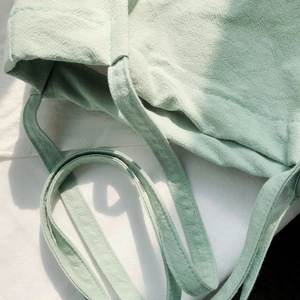 Close-up of light green cotton linen bag showing stitching details and strap texture