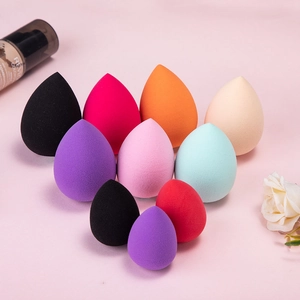 Macro view of ten colorful non-latex makeup sponges in drop shapes with foundation bottle