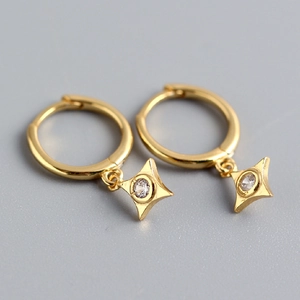 Macro shot of gold hoop earrings featuring sparkling diamond-encrusted star pendants