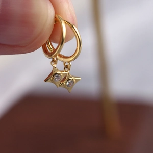 Macro shot of gold hoop earring featuring a star pendant with a sparkling zircon stone