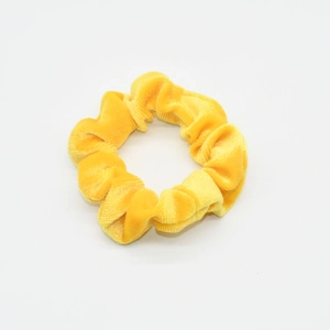 Detail view of the yellow velvet scrunchie showing soft texture and elastic design