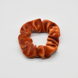 Detailed view of the ribbed corduroy texture and elastic band of this brown hair scrunchie