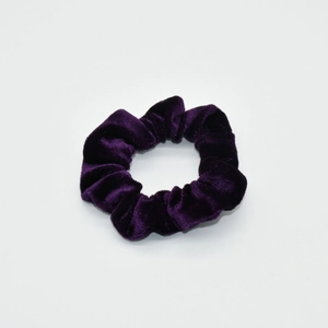 Detail shot of a deep purple velvet scrunchie showing the soft plush texture and elastic band