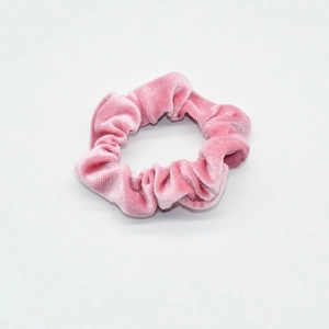 Detailed close-up of a premium pink velvet scrunchie showing soft fabric texture on white