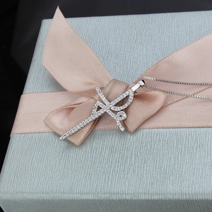 Detail of silver cross pendant with sparkling stones on a light blue gift box