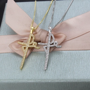 Gold and silver cross necklaces with pave-set crystals on a blue gift box