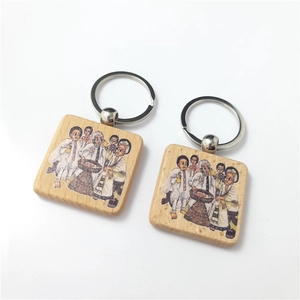 Detail of square beech wood keychains with metal rings and cultural ritual illustration