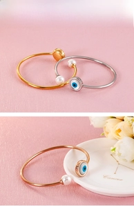 Detailed close-up of lucky evil eye bangle with pearls in gold, silver and rose gold
