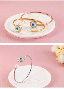 Detailed view of evil eye and pearl bangle in gold, rose gold and silver finishes
